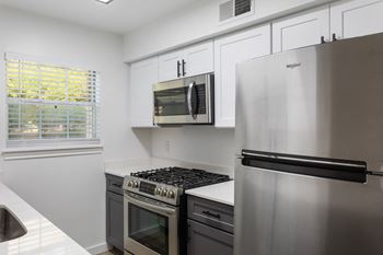 an empty kitchen with stainless steel appliances and white cabinets